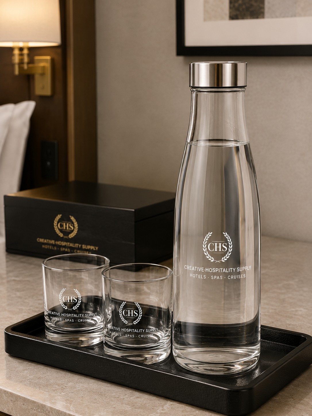 Glasflasche mit zwei Gläsern und CHS-Logo auf Tablett